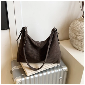 Detail of dark brown leather tote bag with stitching on a silver suitcase