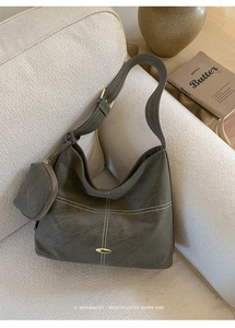 Detail of hobo tote bag with white stitching, wide strap, and round coin purse on sofa