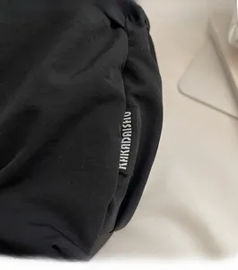 Detailaufnahme der schwarzen Umhängetasche mit dem gewebten Markenlabel HUKADAISHU