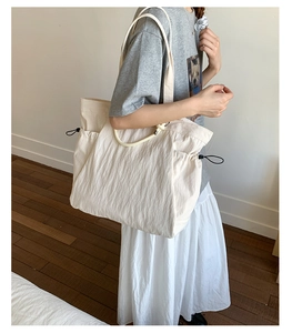 Detail of off-white oversized tote bag showing drawstring sides and ruched nylon texture