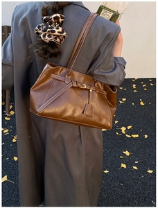 Close-up of vintage brown leather tote bag with gold buckle and smooth stitched straps