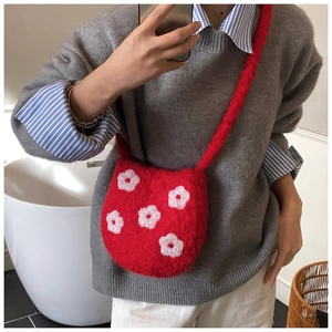 Mirror selfie showing the fluffy red plush crossbody bag with white embroidered flowers
