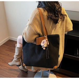 Détail du grand sac cabas noir avec anses en cuir marron et porte-clé bohème élégant