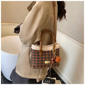Detail of plaid bucket bag featuring fuzzy fleece trim and cute orange fur pompom charm