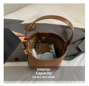 Internal capacity of the dark brown suede bucket bag showing storage for phone and cosmetics