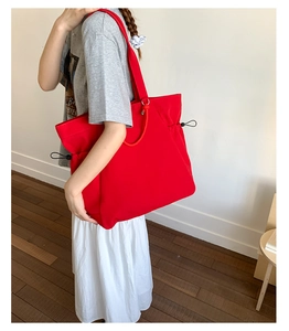 Side view of a red large-capacity tote bag with drawstring details on a female model