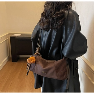 Détail du sac bandoulière en daim marron foncé avec breloque ours sur un mannequin