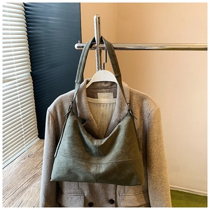 Detailed close-up of an olive green hobo bag on a grey suit showing its matte leather texture