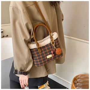 Detail view of plaid shoulder bag with faux fur trim and gold hardware on a model