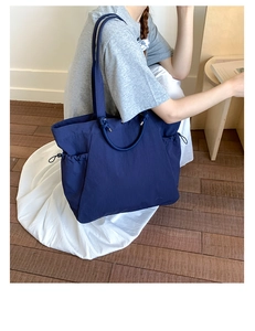 Detail of navy nylon tote bag with drawstring side pockets and dual carry straps