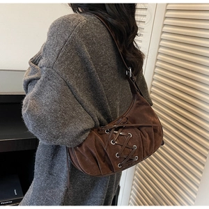 Detail of dark brown suede shoulder bag with corset-style lace-up straps and pleated texture