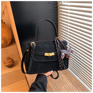 Detail of black textured leather handbag featuring golden lock and horse charm