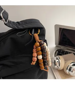 Detail eines Vintage-Perlenanhängers mit braun-weißen Perlen an einer Umhängetasche