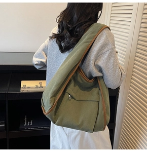 Detail of army green corduroy tote bag featuring contrast brown trim and a zip pocket