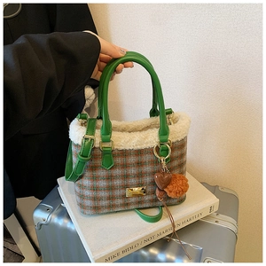 Detail of plaid bucket bag with faux shearling trim and green leather handles