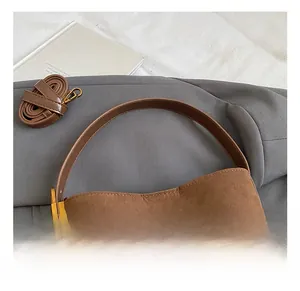 Close-up of brown suede bucket bag with adjustable leather strap and vintage gold hardware
