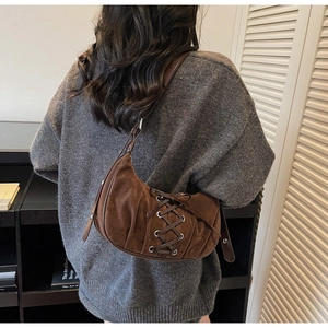 Detailed close-up of brown suede hobo bag featuring lace-up details and metal eyelets