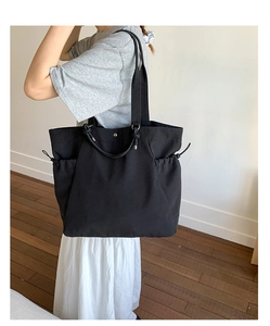 Detail of black canvas tote bag showing side drawstring pocket and magnetic closure