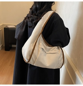 Detailed close-up of beige corduroy tote bag featuring brown trim and front zipper pocket