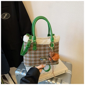 Detail of plaid plush bucket bag with green leather strap and furry heart charm decoration