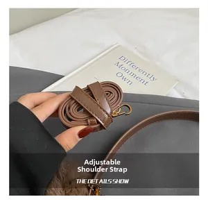Detail of adjustable brown leather shoulder strap with gold metal swivel hook clasp