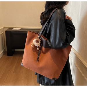 Détail du grand cabas en daim orange-marron avec breloque en peluche et anses en cuir