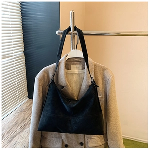 Detail of a black matte leather hobo bag hanging on a hanger for a professional look