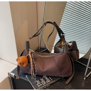 Détail du sac bandoulière en daim marron avec breloque ours et pompon décoratif