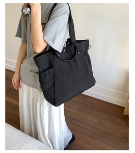 Detail of black large capacity tote bag with side drawstring pocket on model