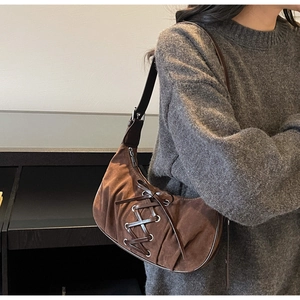 Detail of dark brown faux suede hobo bag featuring silver eyelets and lace-up design