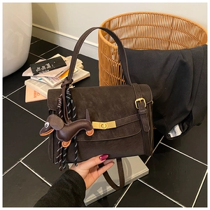 Close-up of a retro dark brown square handbag with a cute dachshund puppy charm