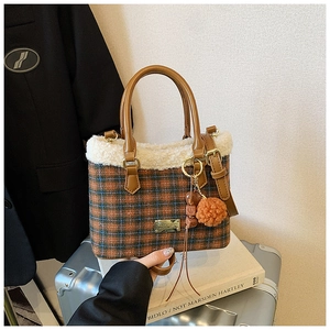 Detail of plaid bucket bag featuring white faux fur trim and gold hardware accents