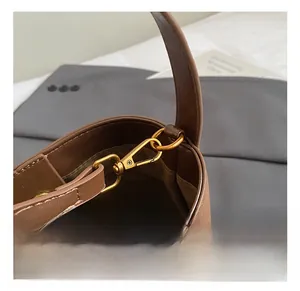 Detailed close-up of brown leather bucket bag with gold metal swivel hook and stitching