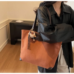 Mannequin portant un grand sac cabas en daim fauve avec des finitions en cuir marron