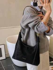 Retro black suede hobo bag with white stitching and gold chain strap on shoulder
