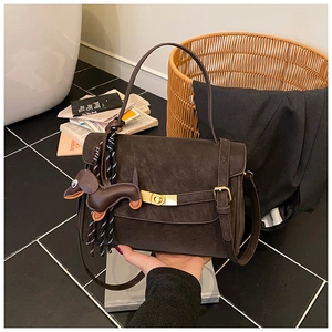 Detail view of brown vintage messenger bag with metal buckle and dachshund charm