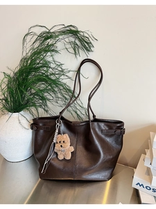 Detail of dark brown suede tote bag featuring soft texture and plush bear pendant detail