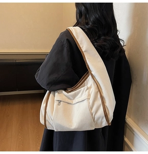 Detail view of cream corduroy tote bag with brown trim and front zipper pocket