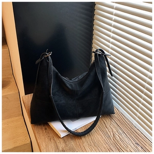 Detail of black suede Hobo bag with vertical stitching on a wooden windowsill
