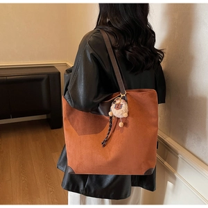 Gros plan du sac cabas en daim marron avec un joli pendentif mouton en peluche blanc