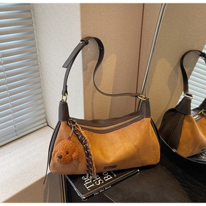 Détail du sac bandoulière en daim marron avec breloque ours en peluche et zip métallique