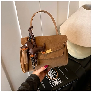 Detailed macro of a vintage brown leather handbag with a golden clasp and puppy charm