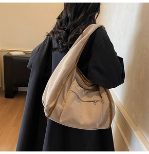 Detail of beige corduroy tote bag with textured stripes and external zipper pocket