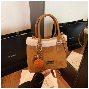 Fashionable brown suede bucket bag featuring white faux fur trim and fluffy pompom detail