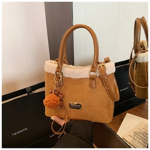 Detailed close-up of brown suede bucket bag with white faux shearling trim and pompom