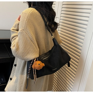 Détail du sac hobo en cuir noir avec charm ours en peluche et logo en métal poli