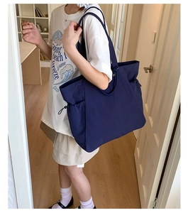Detailed view of spacious navy blue tote bag with side drawstring pockets on model