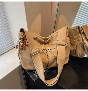 Detail der khakifarbenen Messenger Bag aus Nylon mit Holzperlen und verstellbarem Gurt