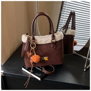 Detail view of brown suede bucket bag featuring faux shearling trim and cute heart charms