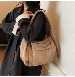 Close-up of beige corduroy tote bag featuring vertical texture and front pocket detail
